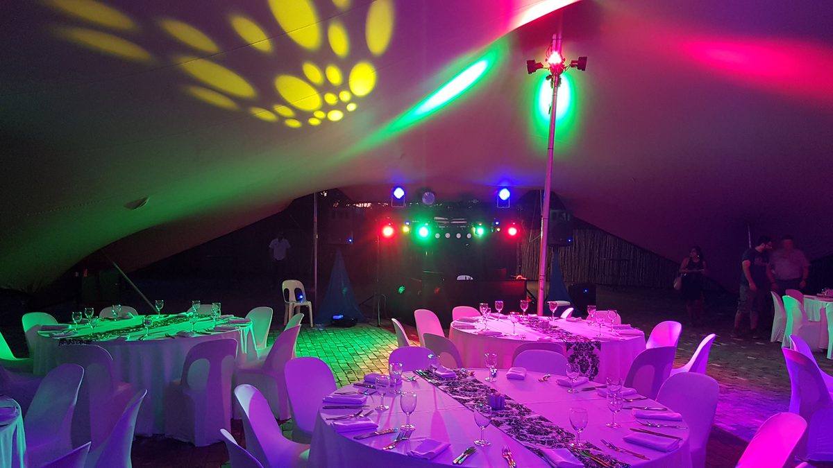 Stretch tent set for a corporate dinner with DJ stage and party lighting