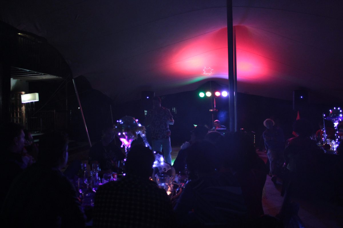 DJ playing to guests in a stretch tent at a night-time party with LED decor