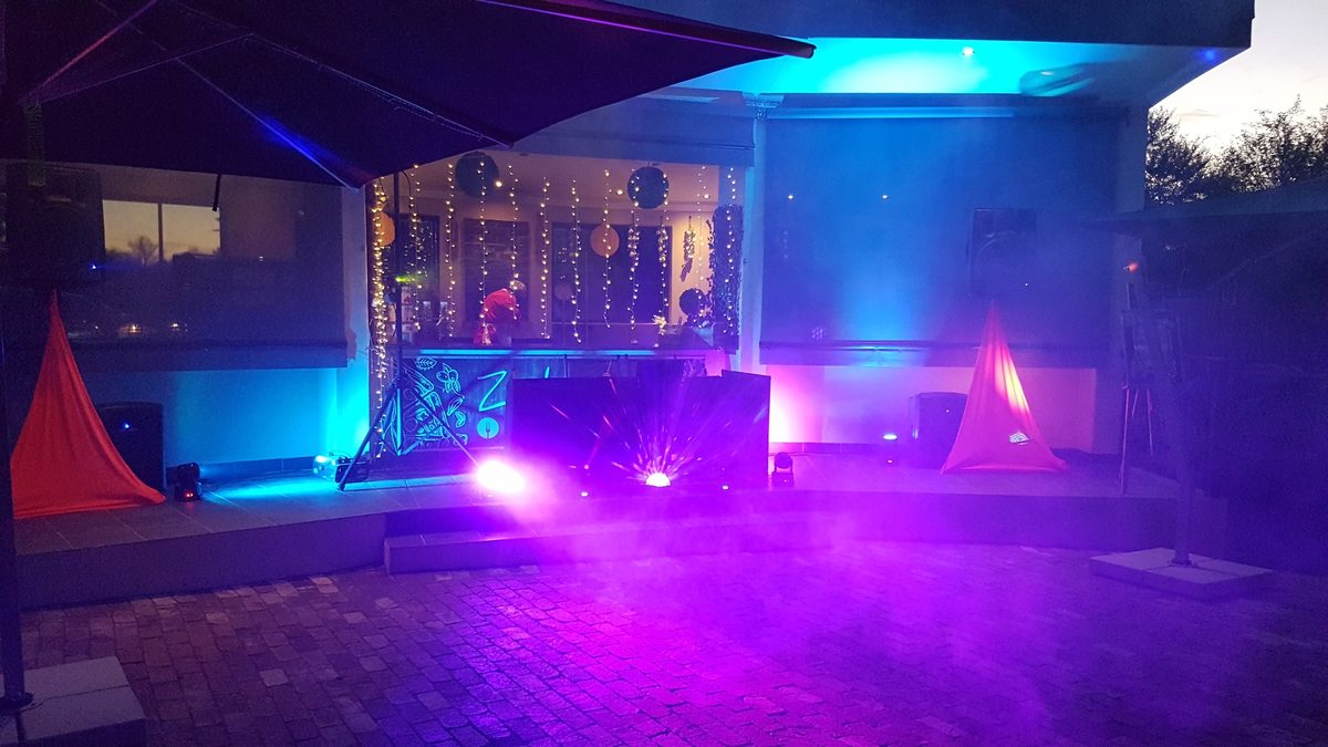 Outdoor DJ stage with speakers, moving lights and purple uplighting